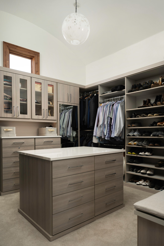 This is an example of a modern walk-in wardrobe in Denver with flat-panel cabinets, carpet, beige floor and vaulted.