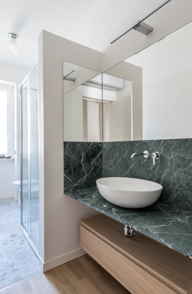 Mid-sized contemporary 3/4 bathroom in Milan with flat-panel cabinets, light wood cabinets, a corner shower, a wall-mount toilet, green tile, matchstick tile, white walls, light hardwood floors, a vessel sink, marble benchtops, beige floor, a sliding shower screen, green benchtops, a single vanity and a floating vanity.