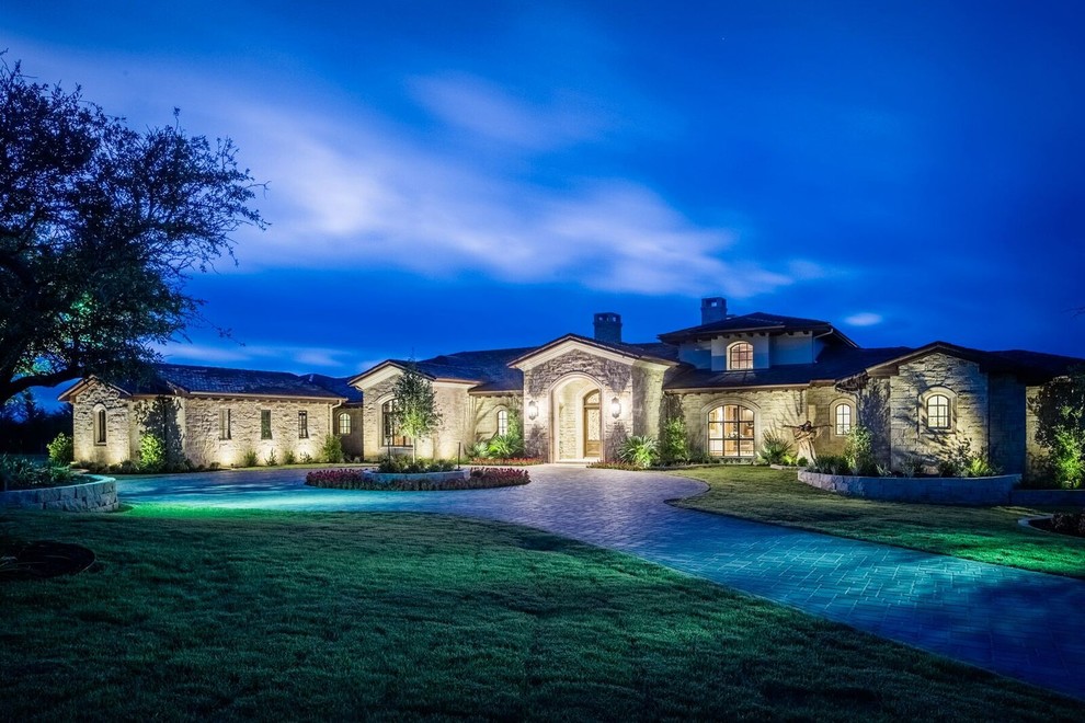 Expansive traditional one-storey beige house exterior in Austin with stone veneer, a gable roof and a mixed roof.