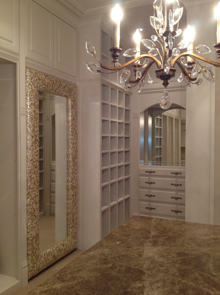 Photo of a large mediterranean women's walk-in wardrobe in Austin with raised-panel cabinets, beige cabinets and carpet.
