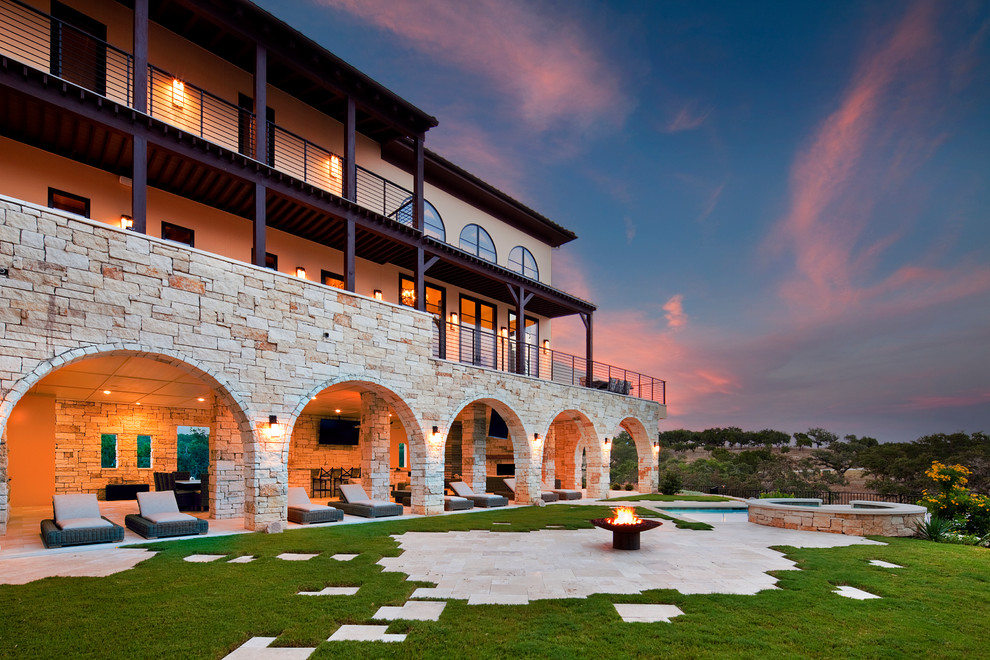 Large mediterranean three-storey beige house exterior in Austin with stone veneer, a flat roof and a shingle roof.