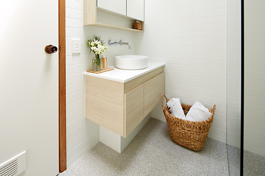 Photo of a small beach style 3/4 bathroom in Melbourne with flat-panel cabinets, light wood cabinets, a corner shower, a wall-mount toilet, ceramic tile, mosaic tile floors, a vessel sink and solid surface benchtops.