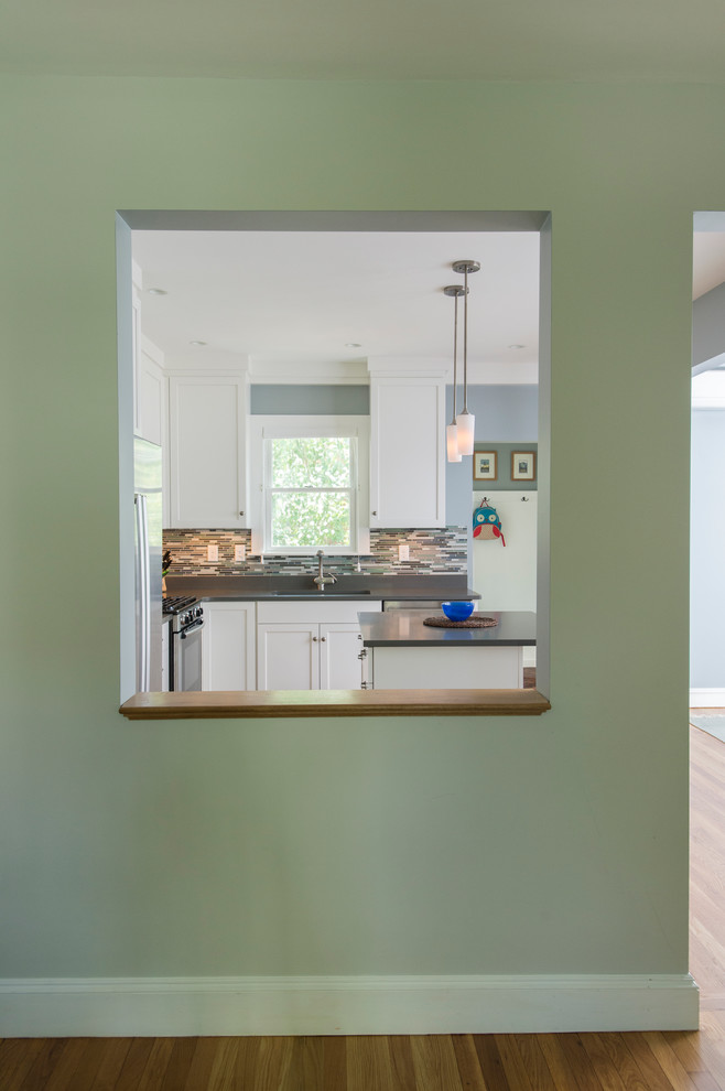 Eat-in kitchen - mid-sized transitional l-shaped medium tone wood floor eat-in kitchen idea in Boston with shaker cabinets, white cabinets, quartz countertops, gray backsplash, glass sheet backsplash, stainless steel appliances, an island and a single-bowl sink