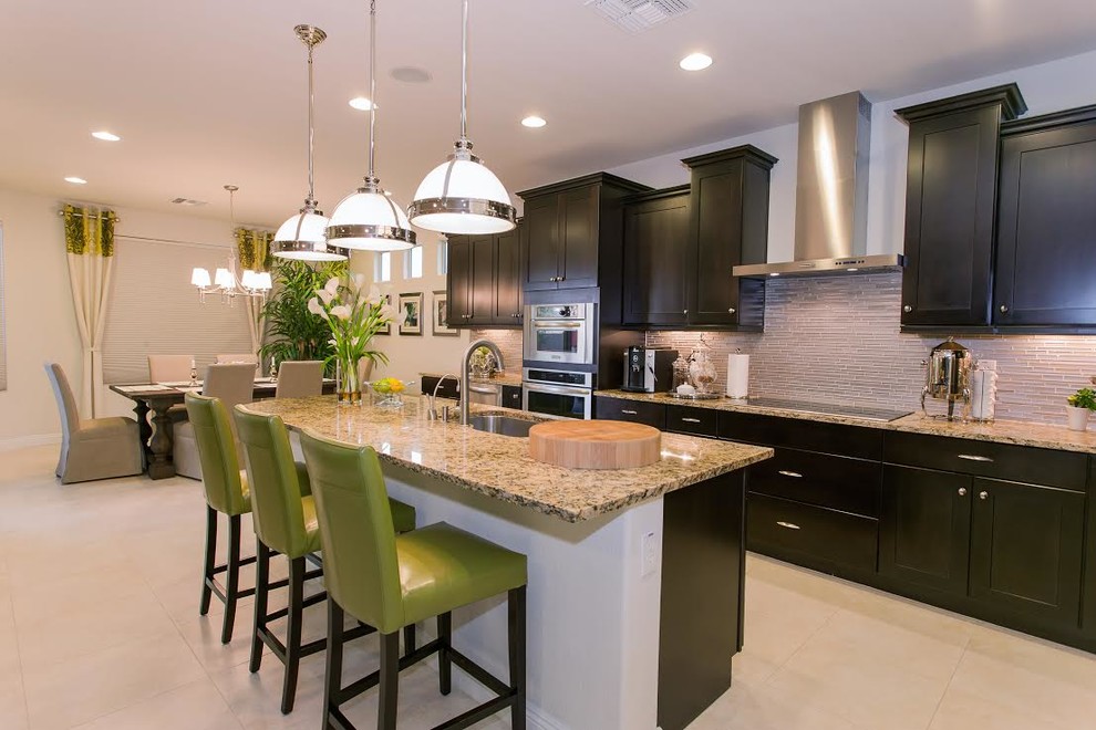Open concept kitchen - large transitional galley beige floor open concept kitchen idea in Denver with an undermount sink, shaker cabinets, black cabinets, granite countertops, gray backsplash, glass tile backsplash, stainless steel appliances and an island
