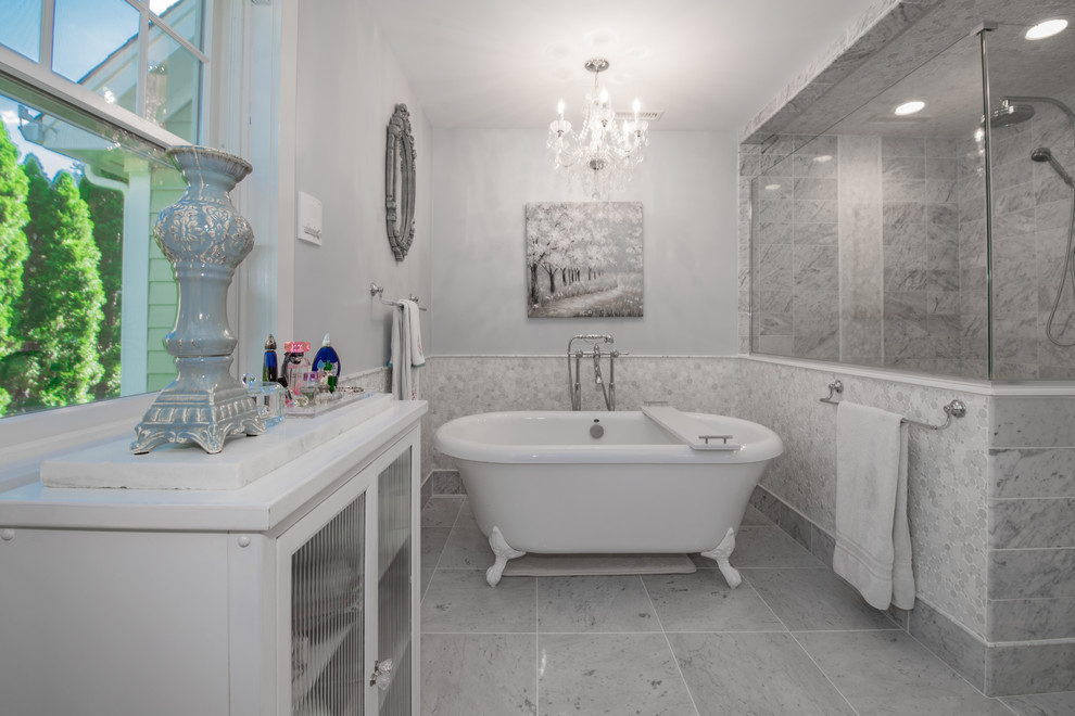 Inspiration for a mid-sized traditional master bathroom in New York with recessed-panel cabinets, white cabinets, blue walls, an undermount sink, granite benchtops, grey floor, multi-coloured benchtops, a freestanding tub, an alcove shower, a two-piece toilet, marble, ceramic floors and a hinged shower door.