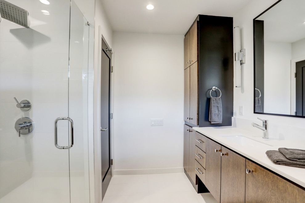 Large midcentury ensuite bathroom in Houston with flat-panel cabinets, medium wood cabinets, an alcove shower, white tiles, porcelain tiles, porcelain flooring, a submerged sink, engineered stone worktops, white floors, a hinged door, white worktops, a shower bench, double sinks and a floating vanity unit.