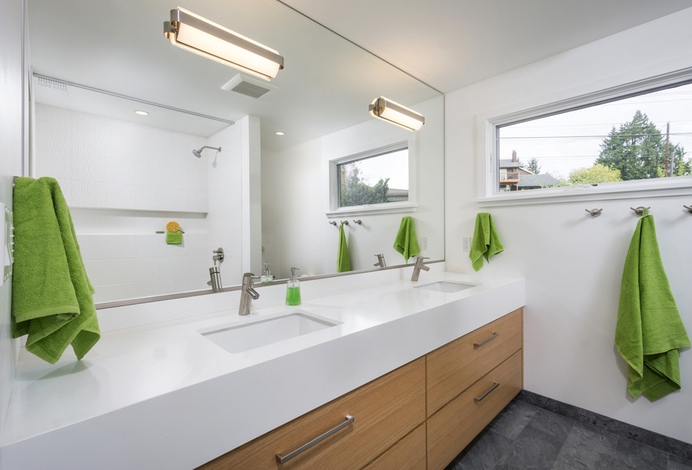Mid-sized contemporary kids bathroom in Portland with flat-panel cabinets, medium wood cabinets, engineered quartz benchtops, white tile, an undermount sink, white walls, white benchtops, an alcove tub, a shower/bathtub combo, a one-piece toilet, ceramic tile, slate floors, grey floor, a double vanity and a built-in vanity.