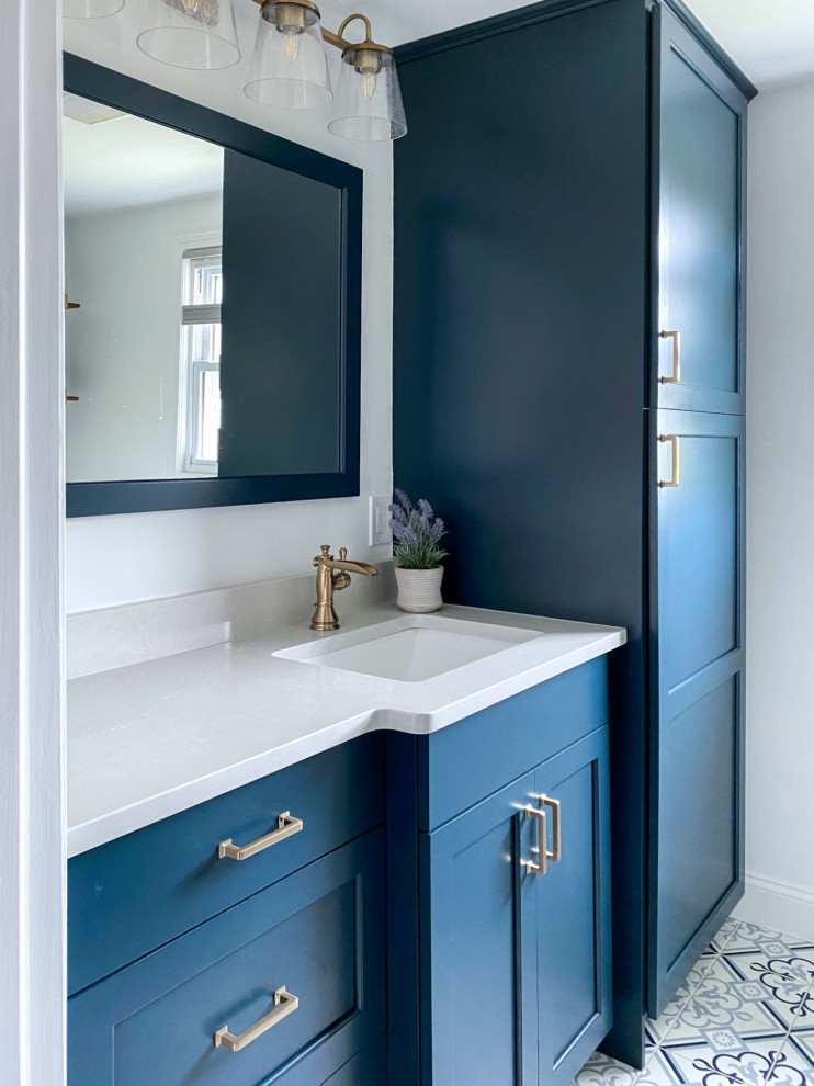 This is an example of a transitional bathroom in Boston with raised-panel cabinets, blue cabinets, an alcove shower, a two-piece toilet, white walls, porcelain floors, an undermount sink, engineered quartz benchtops, blue floor, a hinged shower door, white benchtops, a single vanity and a built-in vanity.