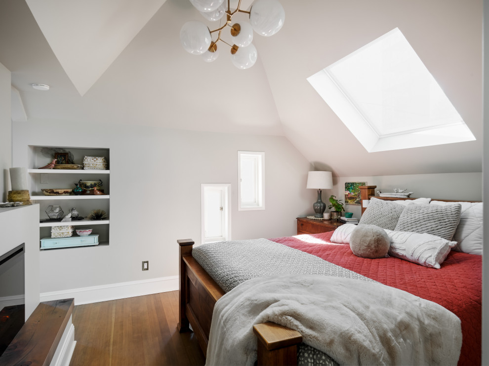 Modelo de dormitorio principal y abovedado de tamaño medio con paredes blancas, suelo de madera en tonos medios, todas las chimeneas y suelo marrón