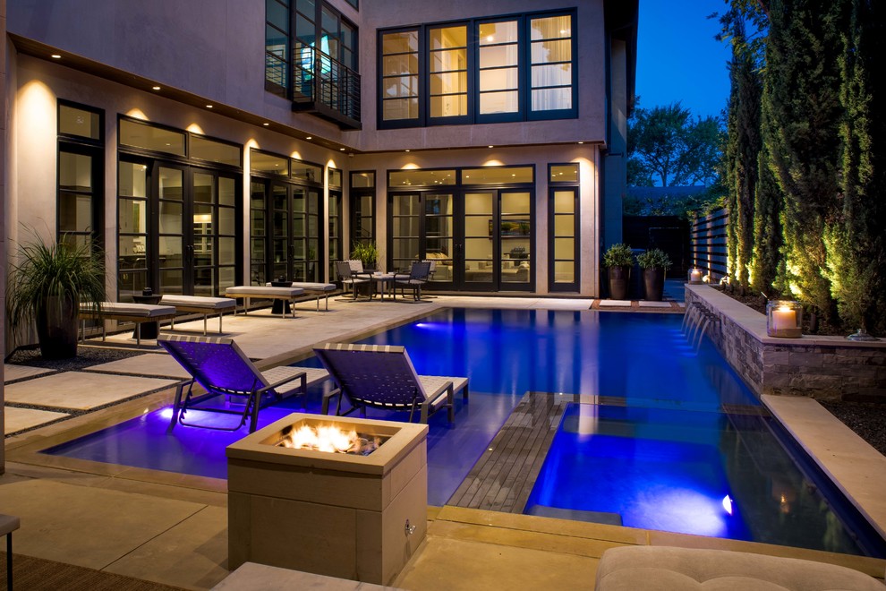 This is an example of a mid-sized modern courtyard rectangular infinity pool in Dallas with a pool house and decking.