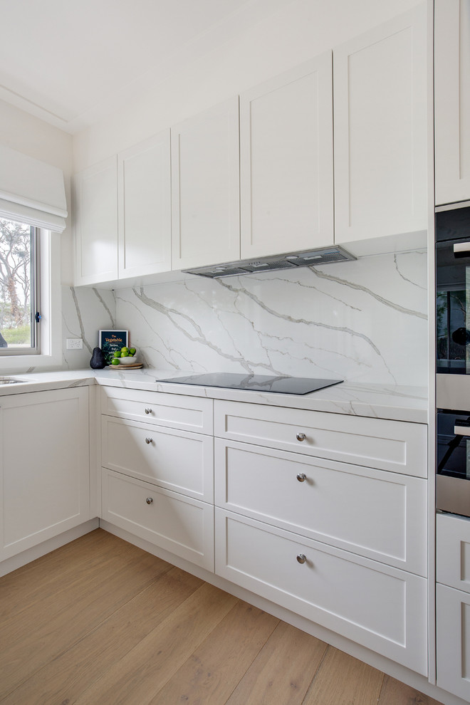 This is an example of a large contemporary u-shaped open plan kitchen in Sydney with shaker cabinets, white cabinets, quartz benchtops, no island and multi-coloured benchtop.