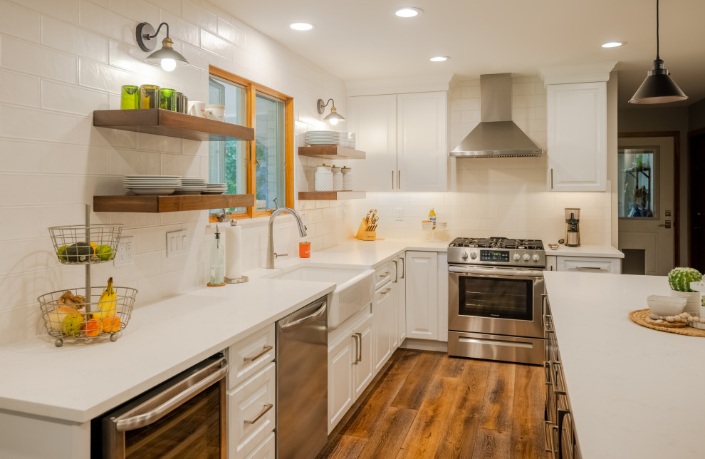 Eat-in kitchen - huge transitional u-shaped medium tone wood floor and brown floor eat-in kitchen idea in Denver with a farmhouse sink, raised-panel cabinets, white cabinets, quartz countertops, white backsplash, ceramic backsplash, stainless steel appliances, an island and white countertops