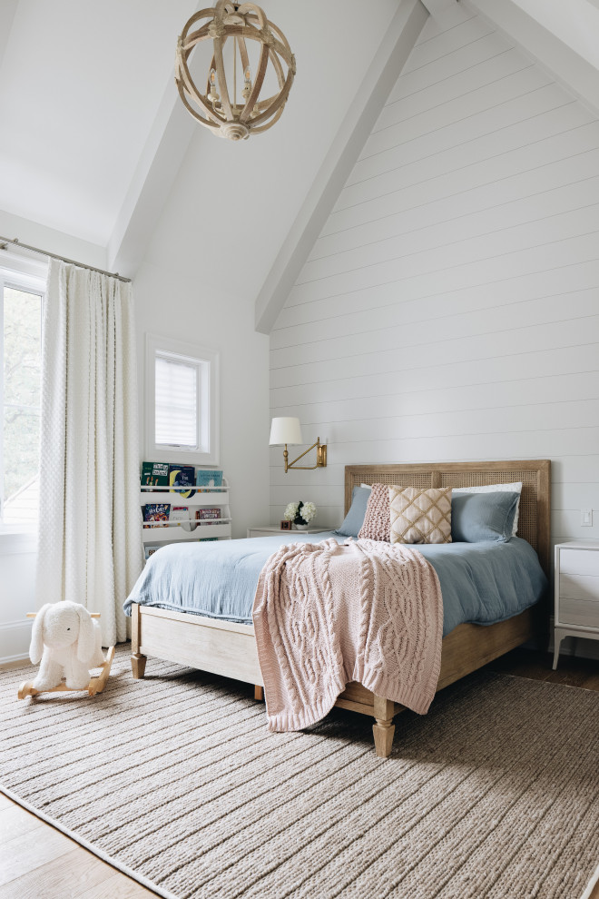 Cette photo montre une grande chambre d'enfant de 1 à 3 ans chic avec un mur blanc, parquet clair, un sol marron, un plafond voûté et du lambris.