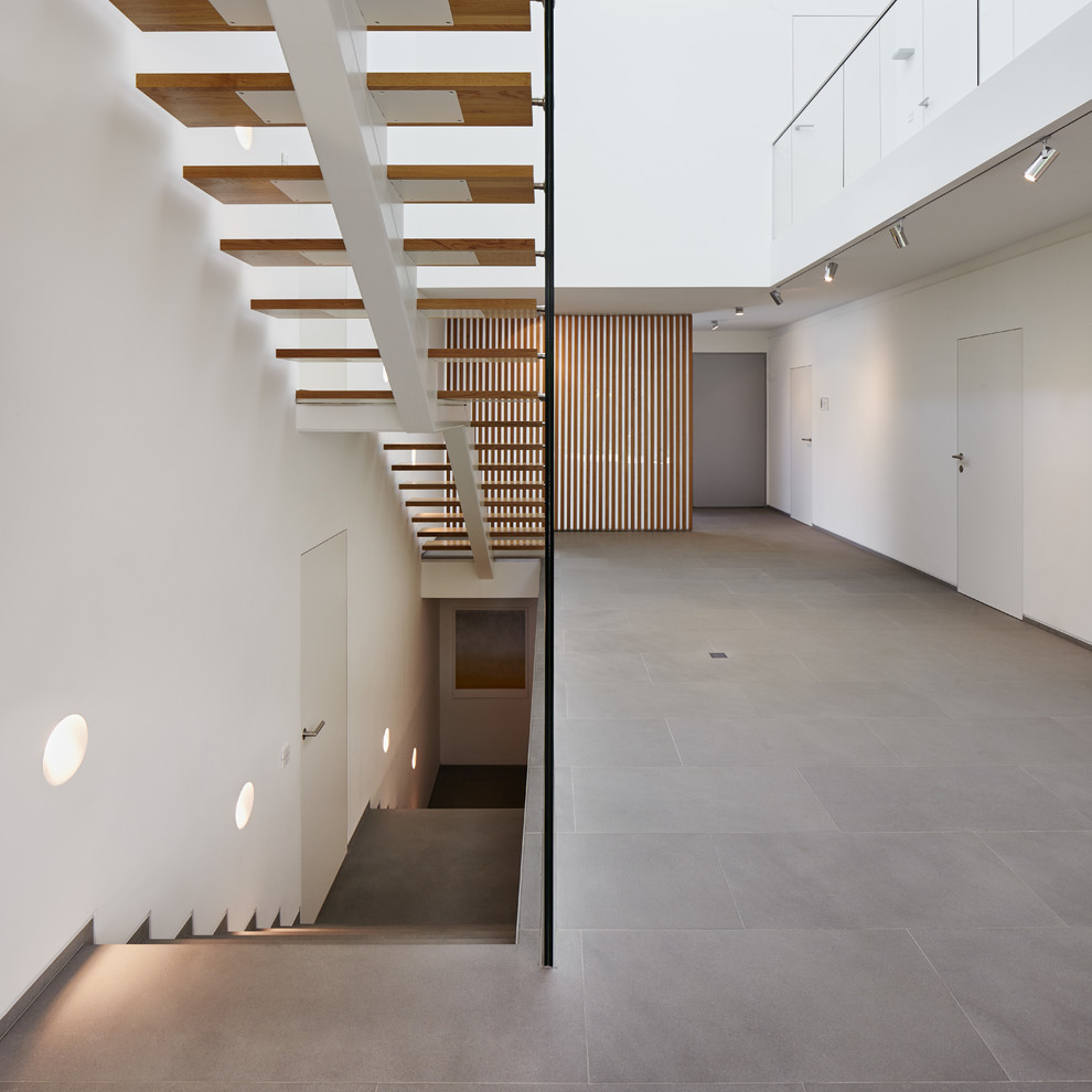 This is an example of an expansive contemporary wood straight staircase in Cologne with open risers.