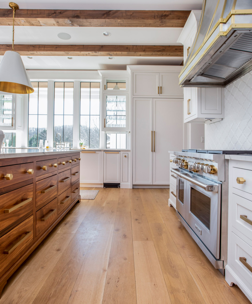 Example of a large country l-shaped light wood floor, brown floor and exposed beam open concept kitchen design in Nashville with a farmhouse sink, beaded inset cabinets, medium tone wood cabinets, marble countertops, white backsplash, stainless steel appliances, an island and white countertops