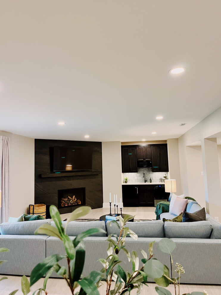 Example of a large minimalist walk-out vinyl floor and beige floor basement design with a bar, beige walls, a corner fireplace and a tile fireplace