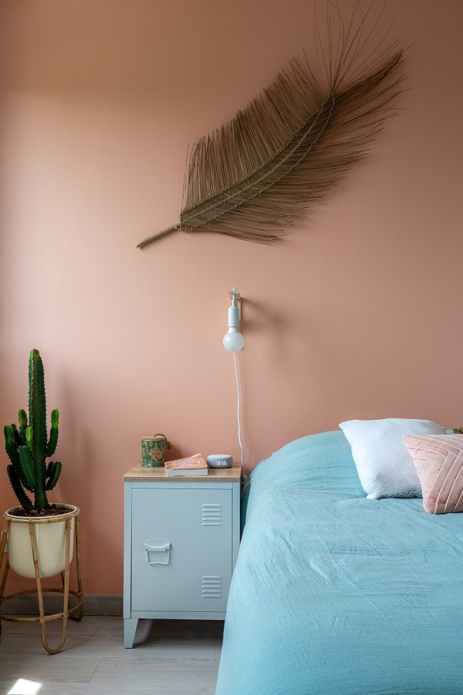 This is an example of a mid-sized beach style bedroom in Lyon with pink walls, painted wood floors and beige floor.