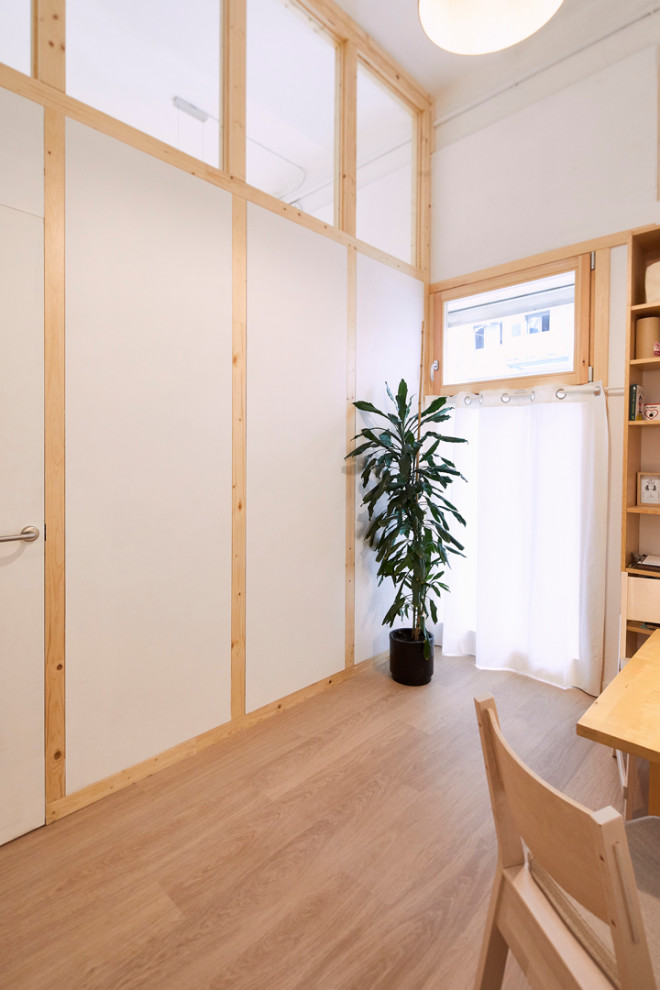 Foto på ett litet skandinaviskt hemmastudio, med vita väggar, ljust trägolv, ett fristående skrivbord och beiget golv