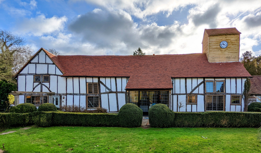 На фото: белый частный загородный дом в классическом стиле с двускатной крышей, черепичной крышей и красной крышей с