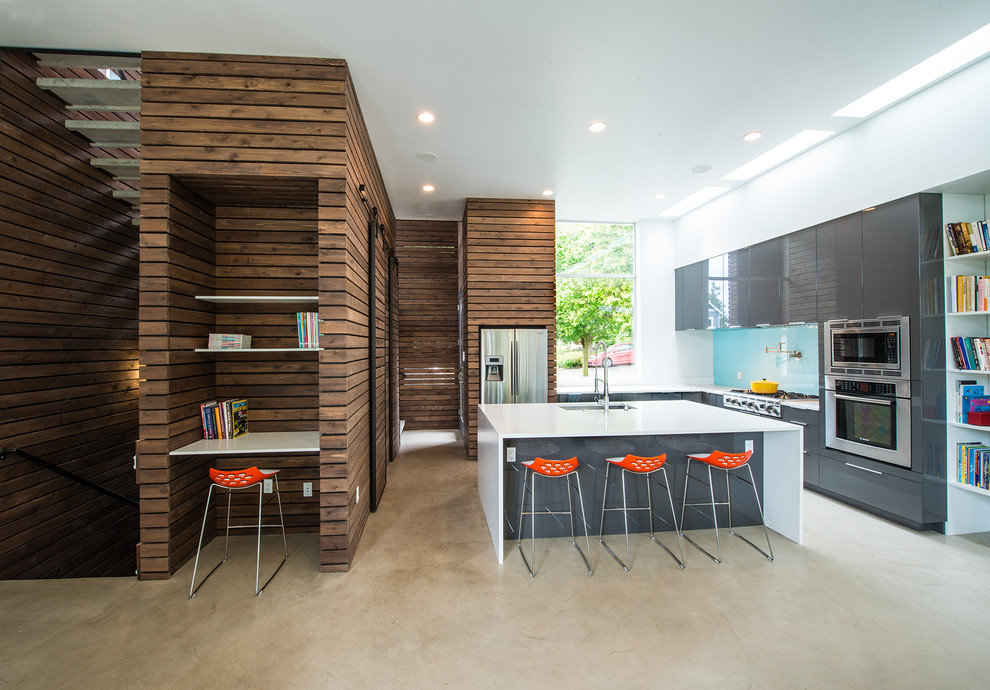 Inspiration for a mid-sized contemporary l-shaped open plan kitchen in Seattle with an undermount sink, flat-panel cabinets, grey cabinets, blue splashback, glass sheet splashback, with island, quartz benchtops, stainless steel appliances and concrete floors.