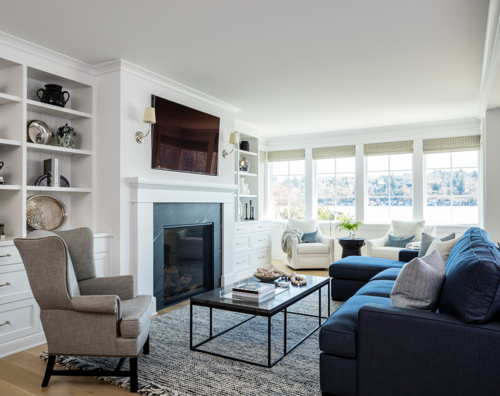 Photo of a beach style living room in Seattle with white walls, medium hardwood floors, a standard fireplace, a wall-mounted tv and brown floor.