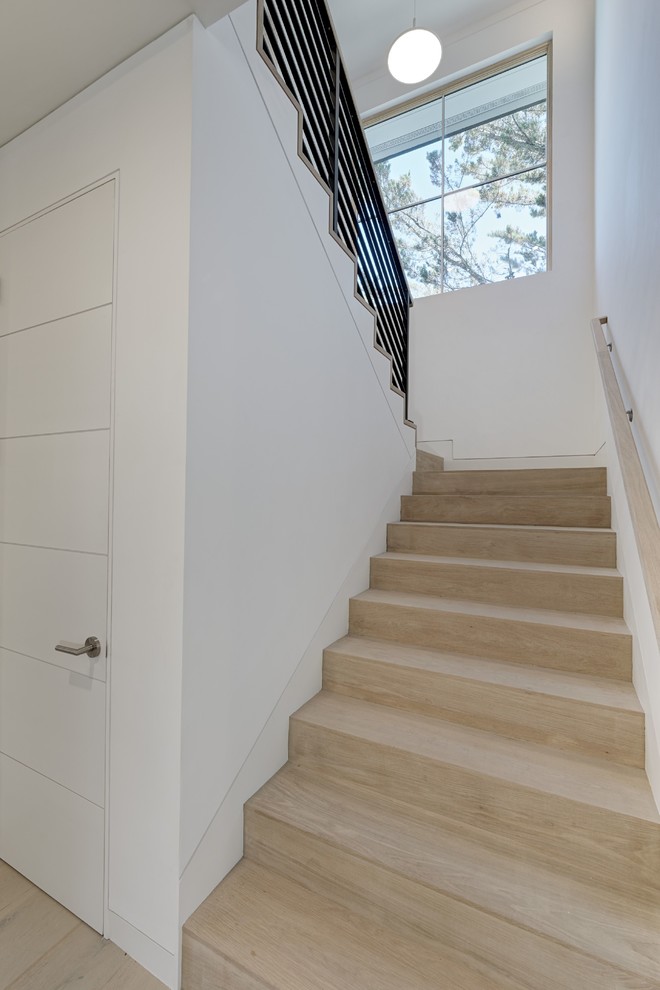 This is an example of a mid-sized transitional wood u-shaped staircase in San Francisco with wood risers and metal railing.