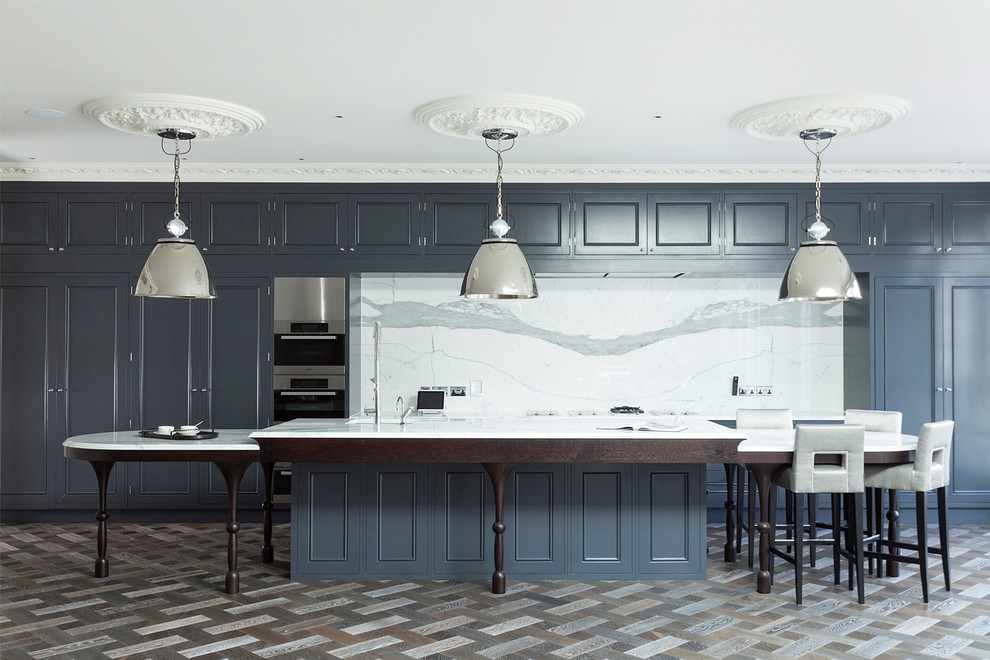 Inspiration for a traditional single-wall kitchen in London with recessed-panel cabinets, grey cabinets, white splashback, stone slab splashback, stainless steel appliances and with island.