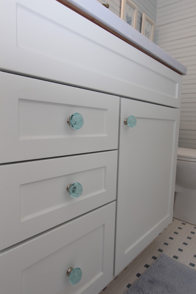Inspiration for a beach style 3/4 bathroom in Grand Rapids with white cabinets, an alcove shower, ceramic floors, an undermount sink, shaker cabinets, solid surface benchtops, a two-piece toilet, multi-coloured tile, ceramic tile and blue walls.