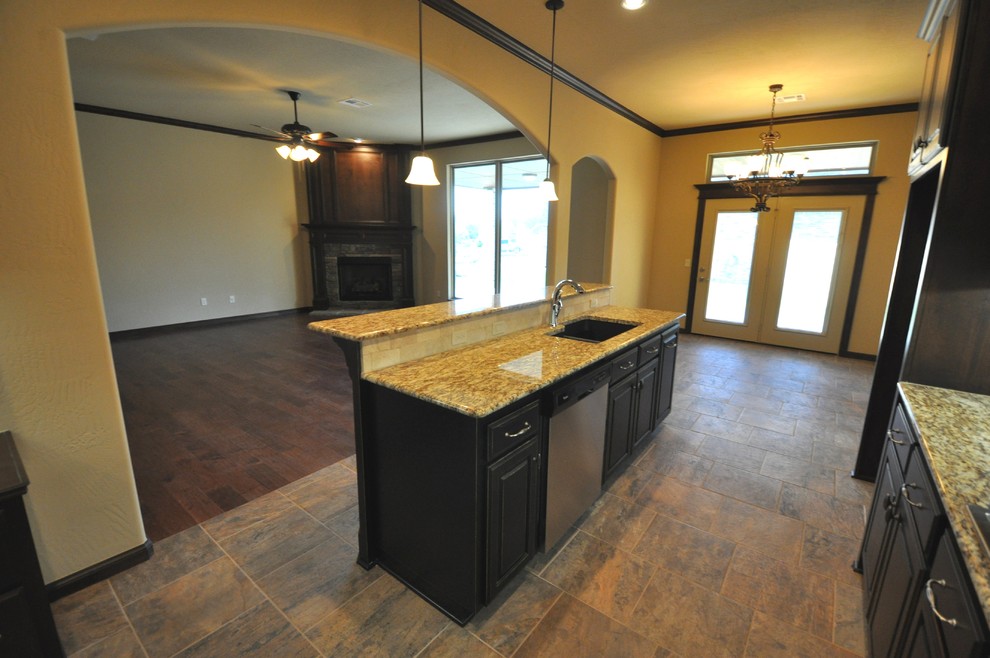 Large traditional l-shaped eat-in kitchen in Oklahoma City with an undermount sink, raised-panel cabinets, dark wood cabinets, granite benchtops, grey splashback, mosaic tile splashback, stainless steel appliances, slate floors and with island.