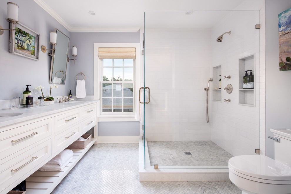 Inspiration for a large beach style master bathroom in New York with white cabinets, a corner shower, a one-piece toilet, white tile, recessed-panel cabinets, ceramic tile, grey walls, ceramic floors, an undermount sink and engineered quartz benchtops.