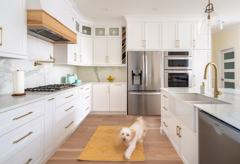 Eat-in kitchen - mid-sized transitional l-shaped light wood floor and brown floor eat-in kitchen idea with a farmhouse sink, shaker cabinets, white cabinets, quartz countertops, yellow backsplash, porcelain backsplash, stainless steel appliances, an island and white countertops