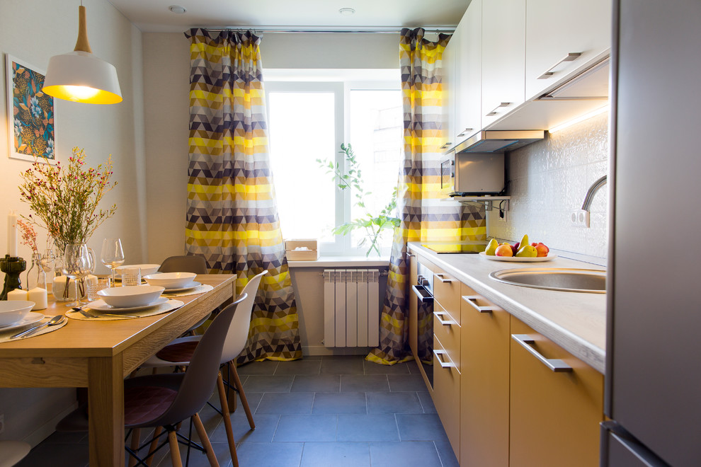 Design ideas for a transitional single-wall kitchen in Moscow with a drop-in sink, flat-panel cabinets, yellow cabinets, white splashback, stainless steel appliances and black floor.