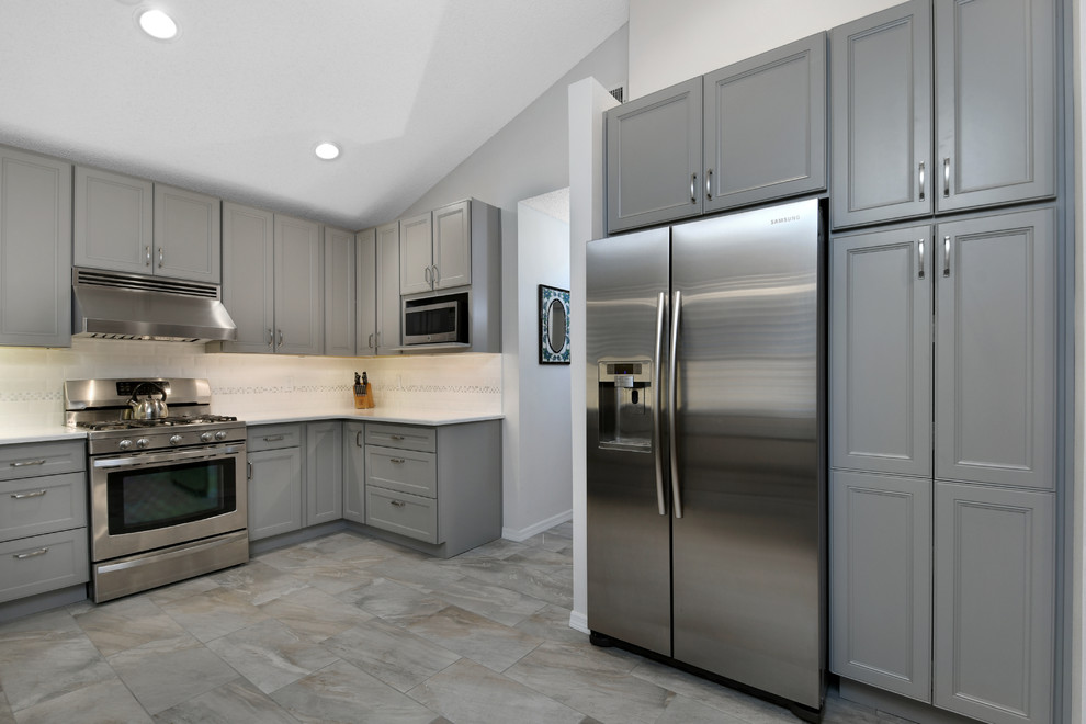 Mid-sized transitional u-shaped ceramic tile and gray floor kitchen photo in Orlando with an undermount sink, beaded inset cabinets, gray cabinets, quartz countertops, white backsplash, subway tile backsplash, stainless steel appliances and no island
