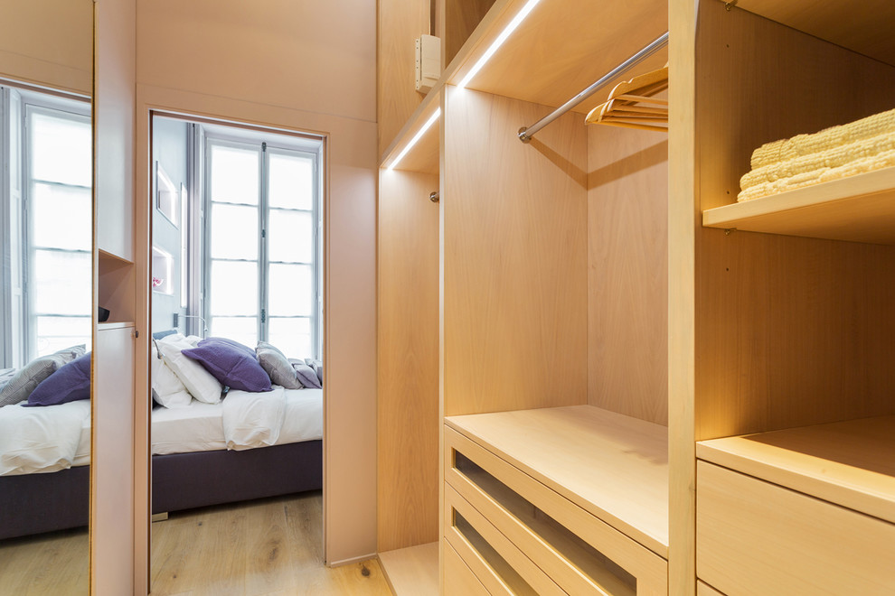 Inspiration for a small contemporary women's dressing room in Paris with open cabinets, light wood cabinets, light hardwood floors and brown floor.