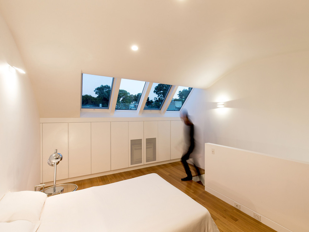 Photo of a small contemporary loft-style bedroom in Sydney with white walls, light hardwood floors and no fireplace.