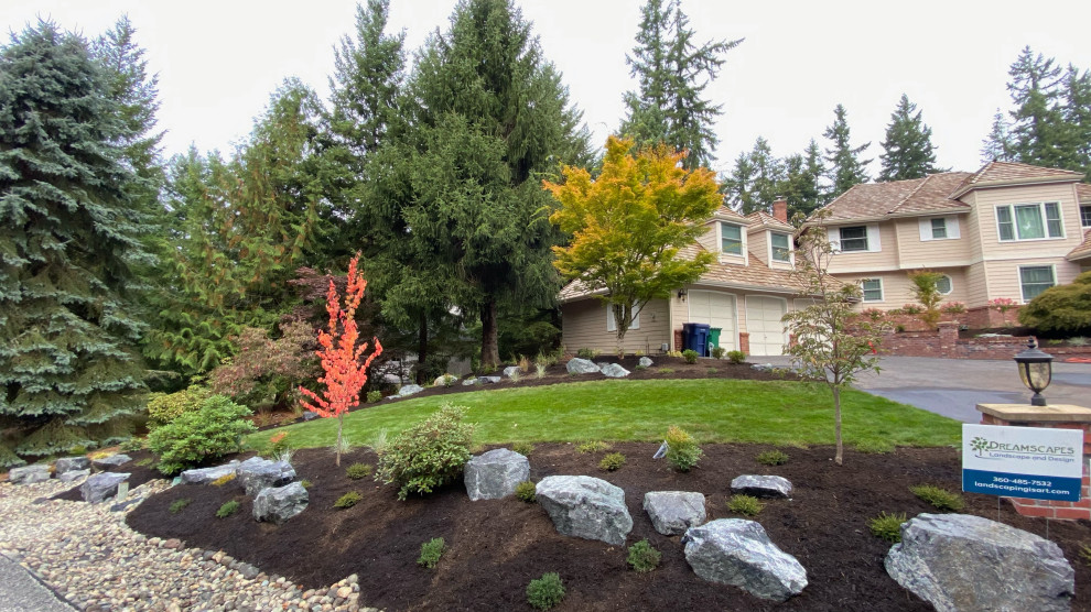 Large sloped partial sun garden in Seattle with with rock feature and mulch.