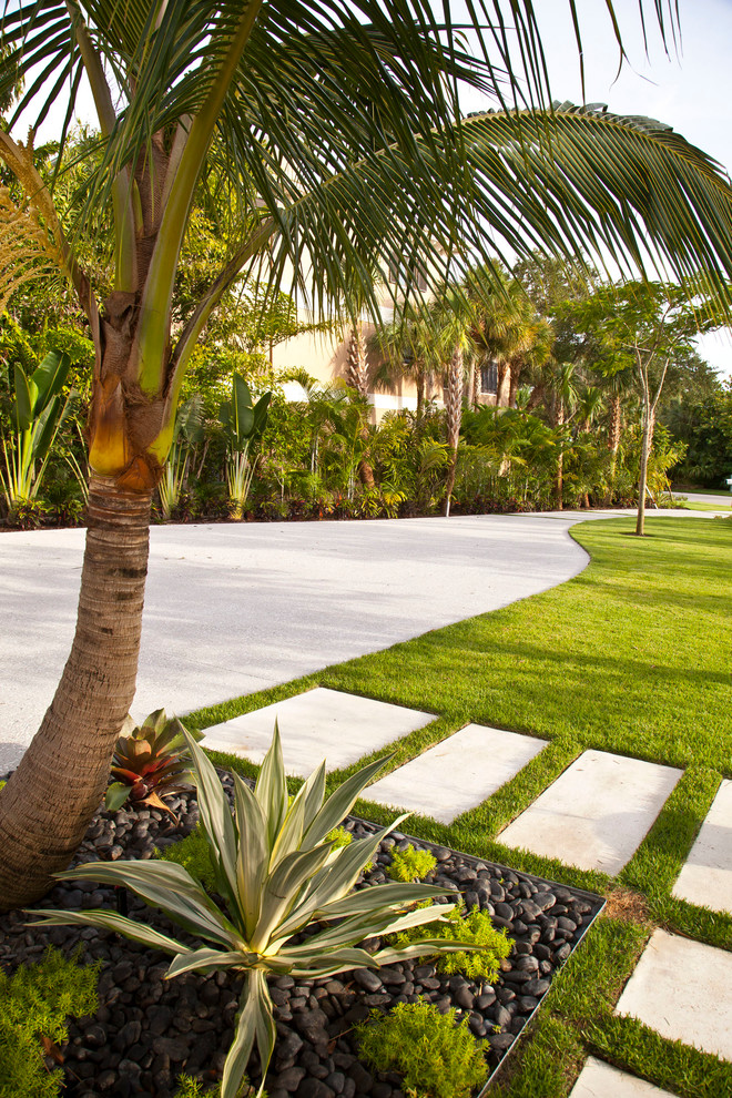 Photo of a large tropical front yard full sun driveway for winter in Tampa with concrete pavers.