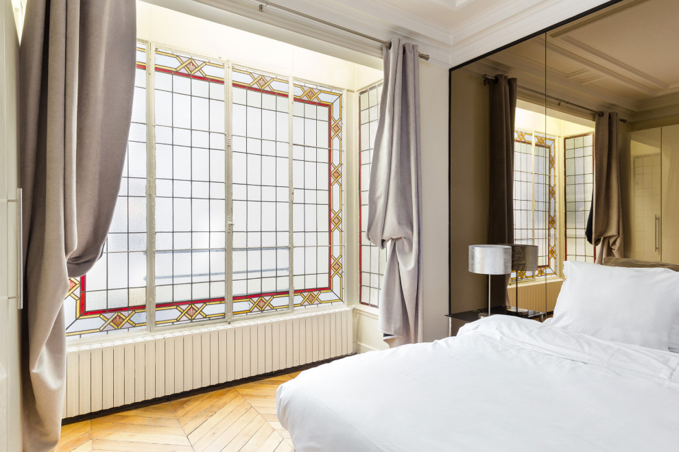 Modelo de dormitorio principal romántico grande con paredes blancas, suelo de madera en tonos medios y suelo beige