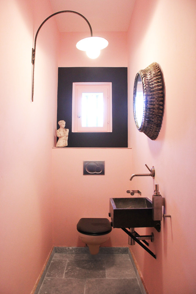 Photo of a small mediterranean powder room in Paris with a wall-mount toilet, pink walls, cement tiles, a wall-mount sink, engineered quartz benchtops and grey floor.