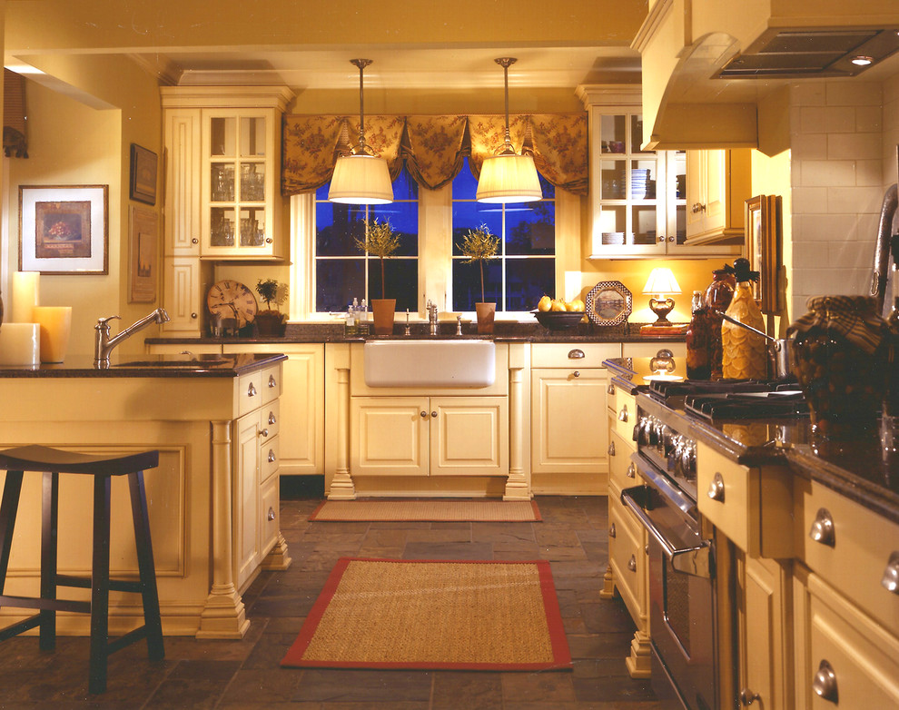 Mid-sized transitional u-shaped slate floor open concept kitchen photo with a farmhouse sink, raised-panel cabinets, yellow cabinets, granite countertops, white backsplash, subway tile backsplash, stainless steel appliances and an island