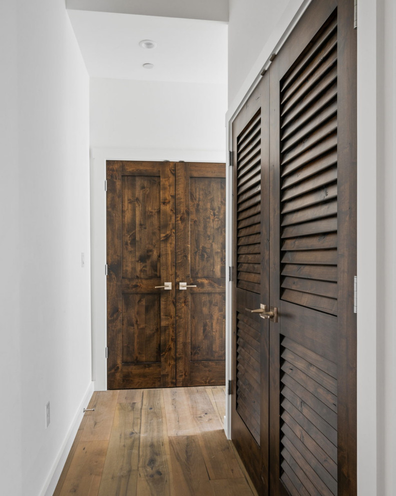 На фото: коридор среднего размера в стиле неоклассика (современная классика) с белыми стенами, паркетным полом среднего тона и коричневым полом