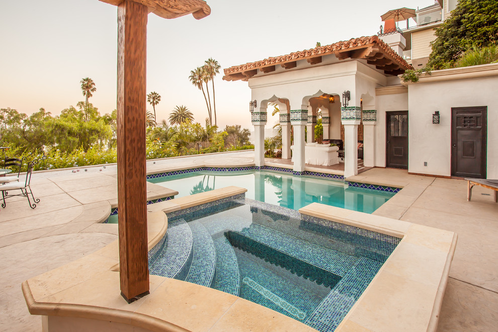 Inspiration for a large mediterranean backyard custom-shaped lap pool in Santa Barbara with a hot tub and stamped concrete.