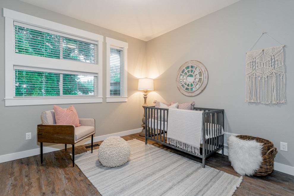 Imagen de habitación de bebé niña de estilo de casa de campo grande con paredes grises, suelo de madera clara y suelo beige