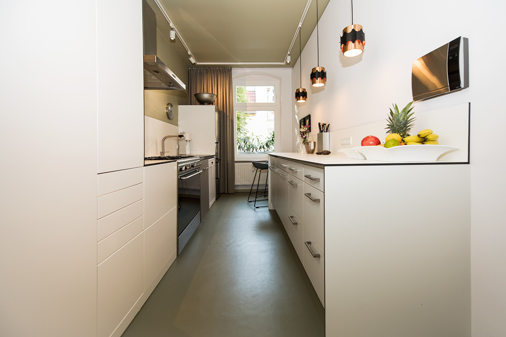 Photo of a small contemporary galley separate kitchen in Berlin with a drop-in sink, flat-panel cabinets, white cabinets, laminate benchtops, white splashback, stainless steel appliances, linoleum floors, no island, green floor and white benchtop.