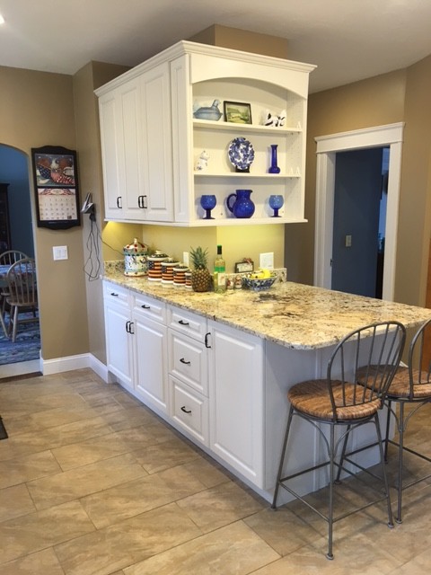 Example of a mid-sized transitional galley porcelain tile eat-in kitchen design in Boston with an undermount sink, raised-panel cabinets, white cabinets, granite countertops, black appliances and an island