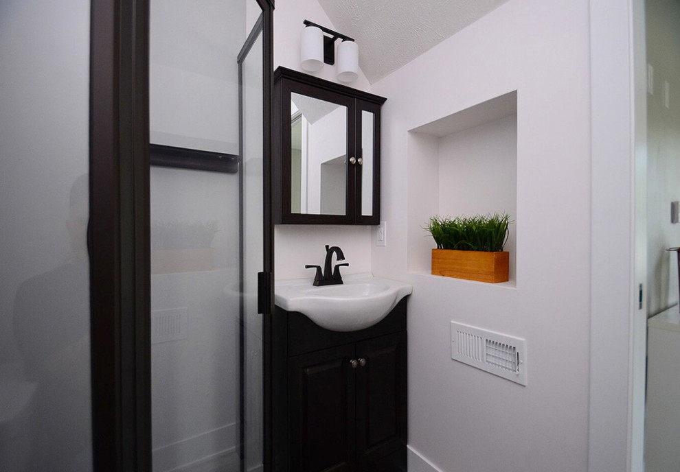 Inspiration for a small modern 3/4 bathroom in Other with furniture-like cabinets, black cabinets, a corner shower, white walls, vinyl floors, a vessel sink, grey floor and a hinged shower door.
