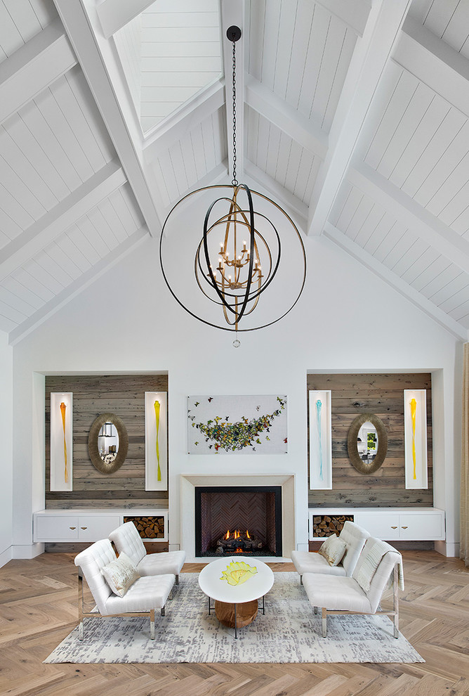 Photo of a country living room with white walls, light hardwood floors, a standard fireplace and beige floor.