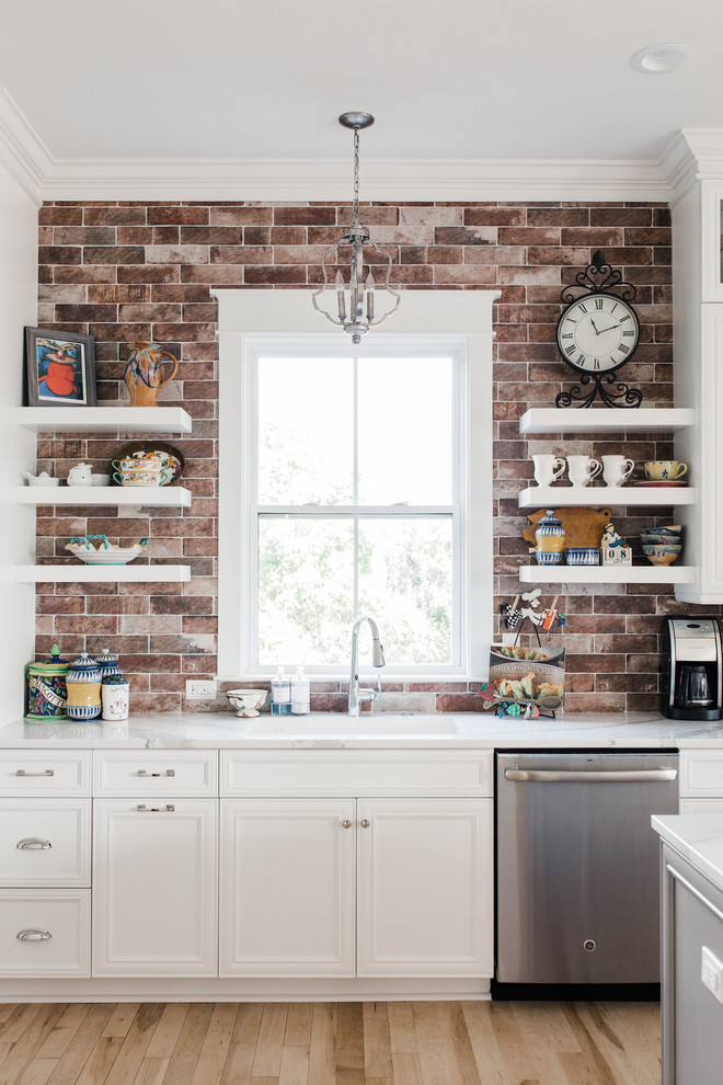 Inspiration for a mid-sized transitional u-shaped eat-in kitchen in Charleston with white cabinets, brick splashback, with island, an undermount sink, shaker cabinets, quartz benchtops, red splashback, stainless steel appliances, light hardwood floors, beige floor and white benchtop.