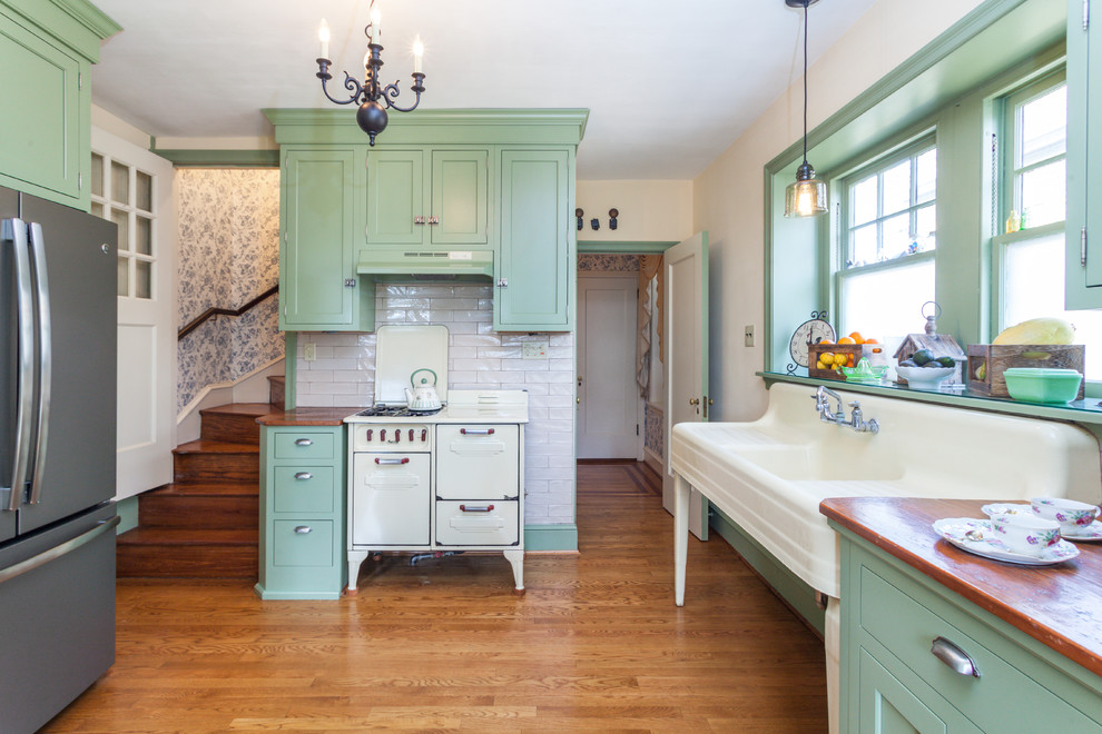 Photo of a traditional eat-in kitchen in Philadelphia with green cabinets, shaker cabinets, wood benchtops, white splashback, subway tile splashback, coloured appliances, medium hardwood floors, brown floor and brown benchtop.