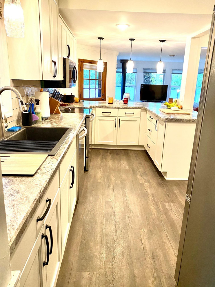 This is an example of a mid-sized contemporary u-shaped eat-in kitchen in Minneapolis with a drop-in sink, shaker cabinets, white cabinets, white splashback, porcelain splashback and vinyl floors.